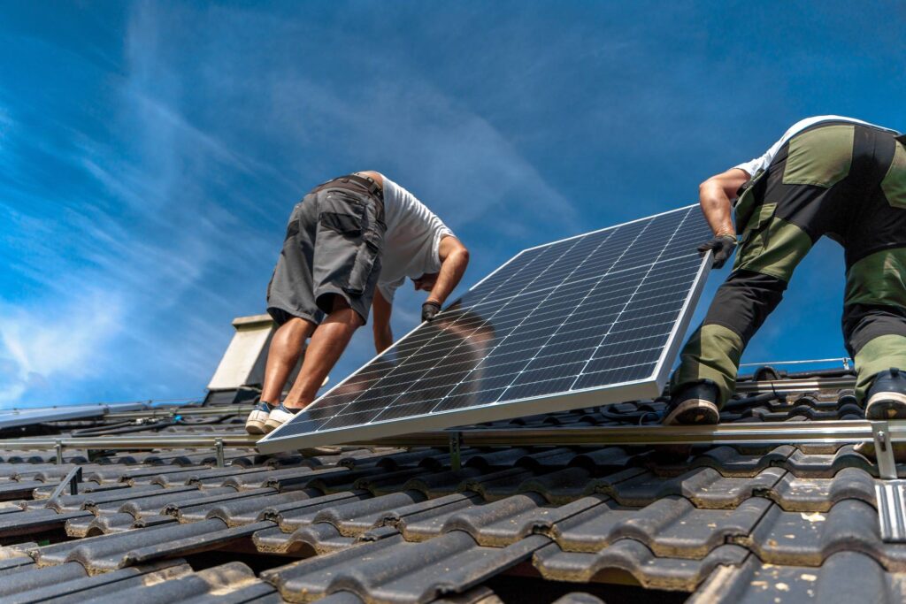 Monterzy instalują panel solarny na dachu